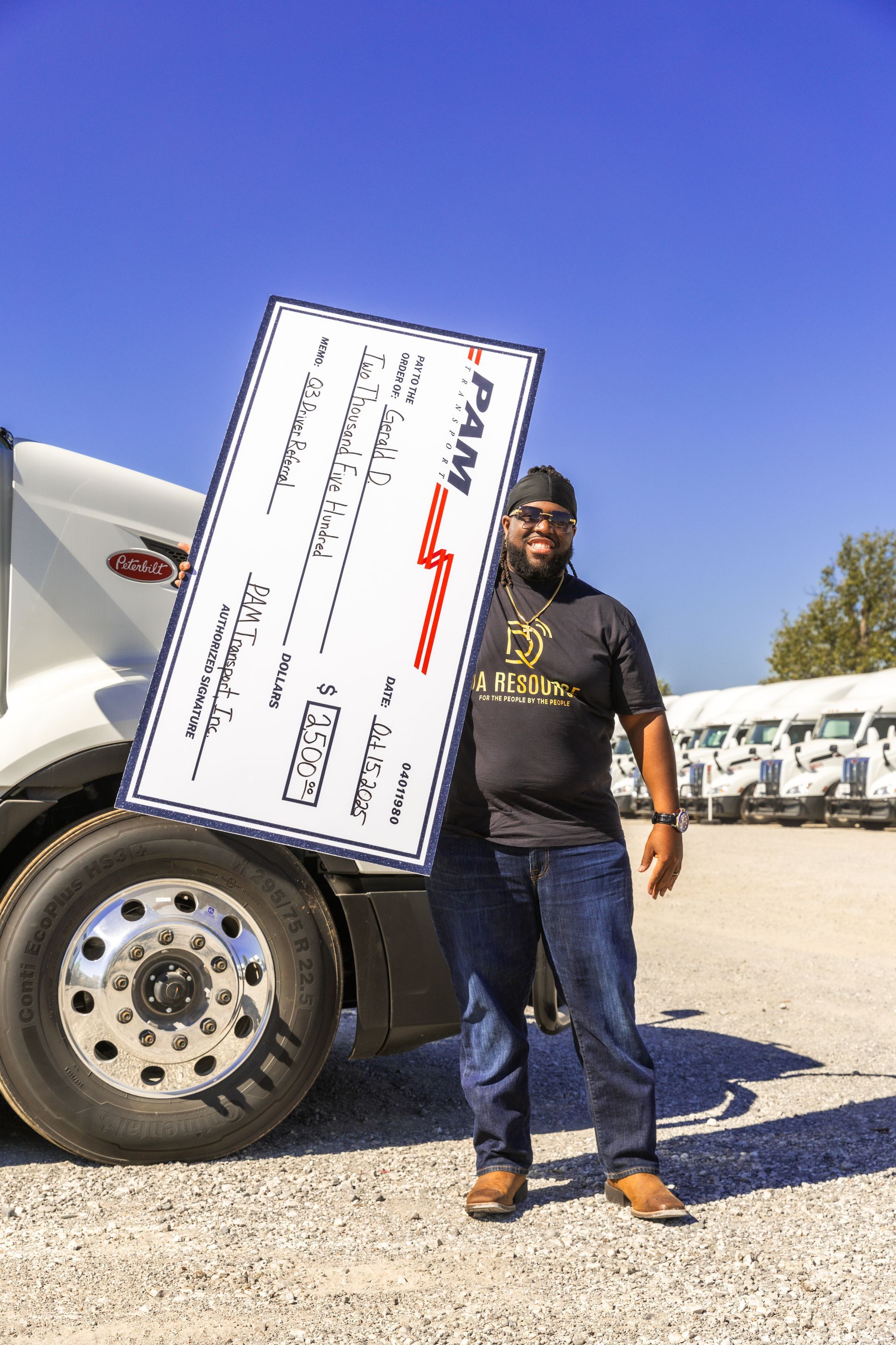 Gerald Drummer holding a PAM Transport driver referral check