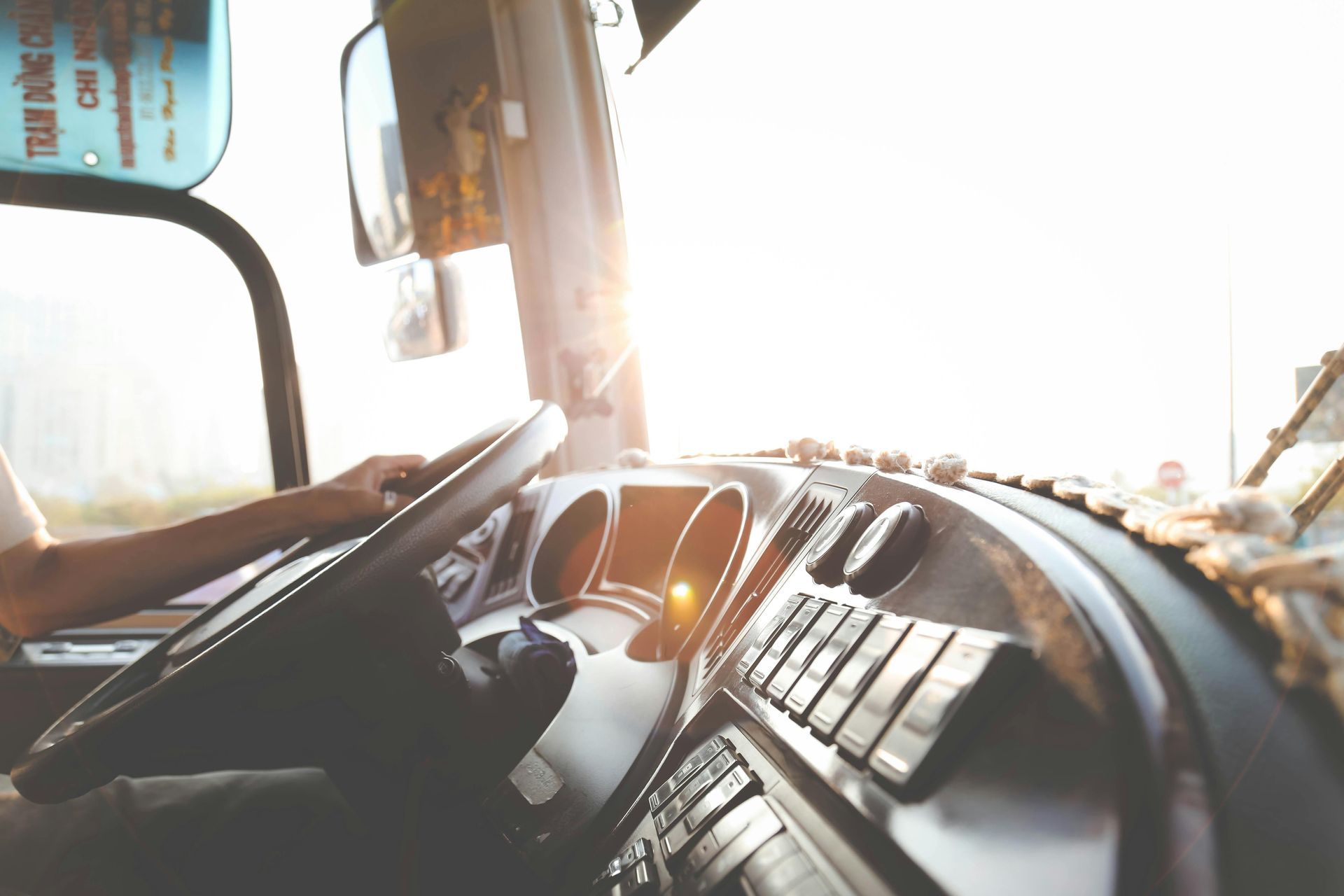 View from a truck cab with hands on the wheel at sunrise